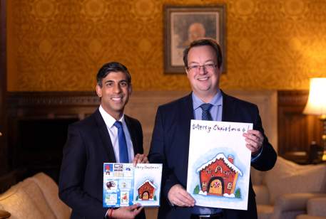 Prime Minister Rishi Sunak with Mike and his 2023 Christmas card showing the winning and runner up designs
